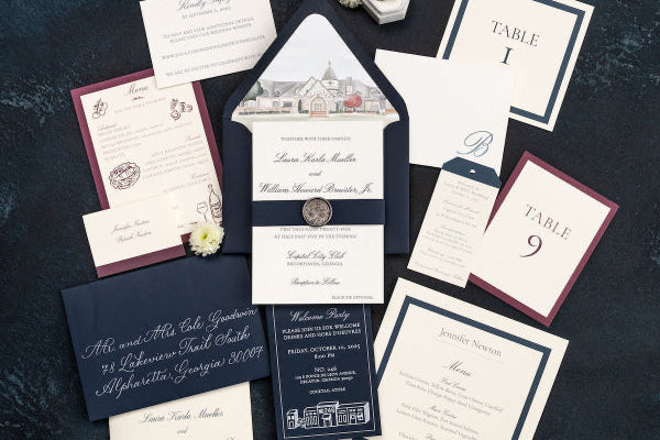 Collection of wedding invitations and stationery items on a dark textured surface.